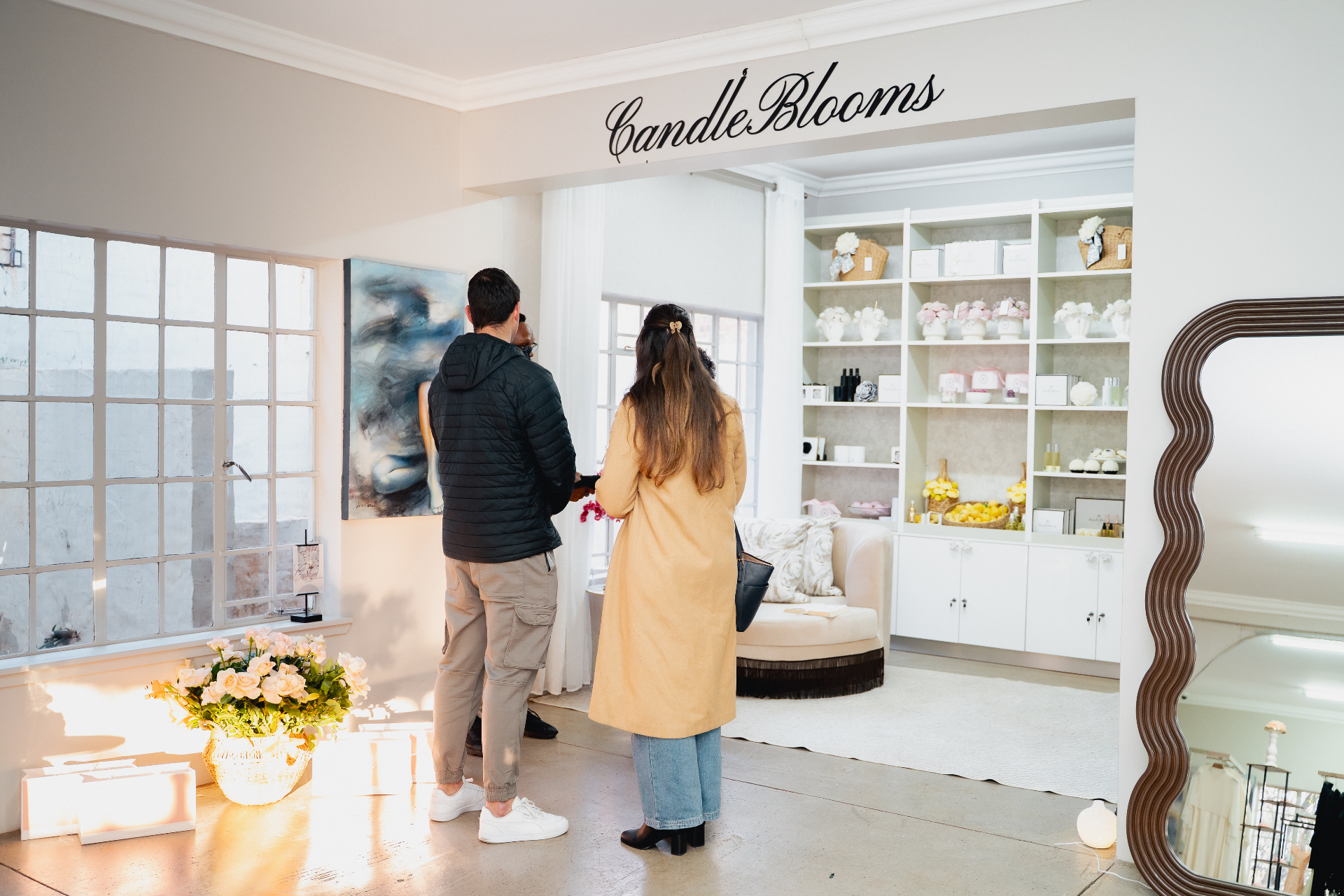 Two guests inside the CandleBlooms showroom, with shelves of floral candles and hand-poured goods in the background